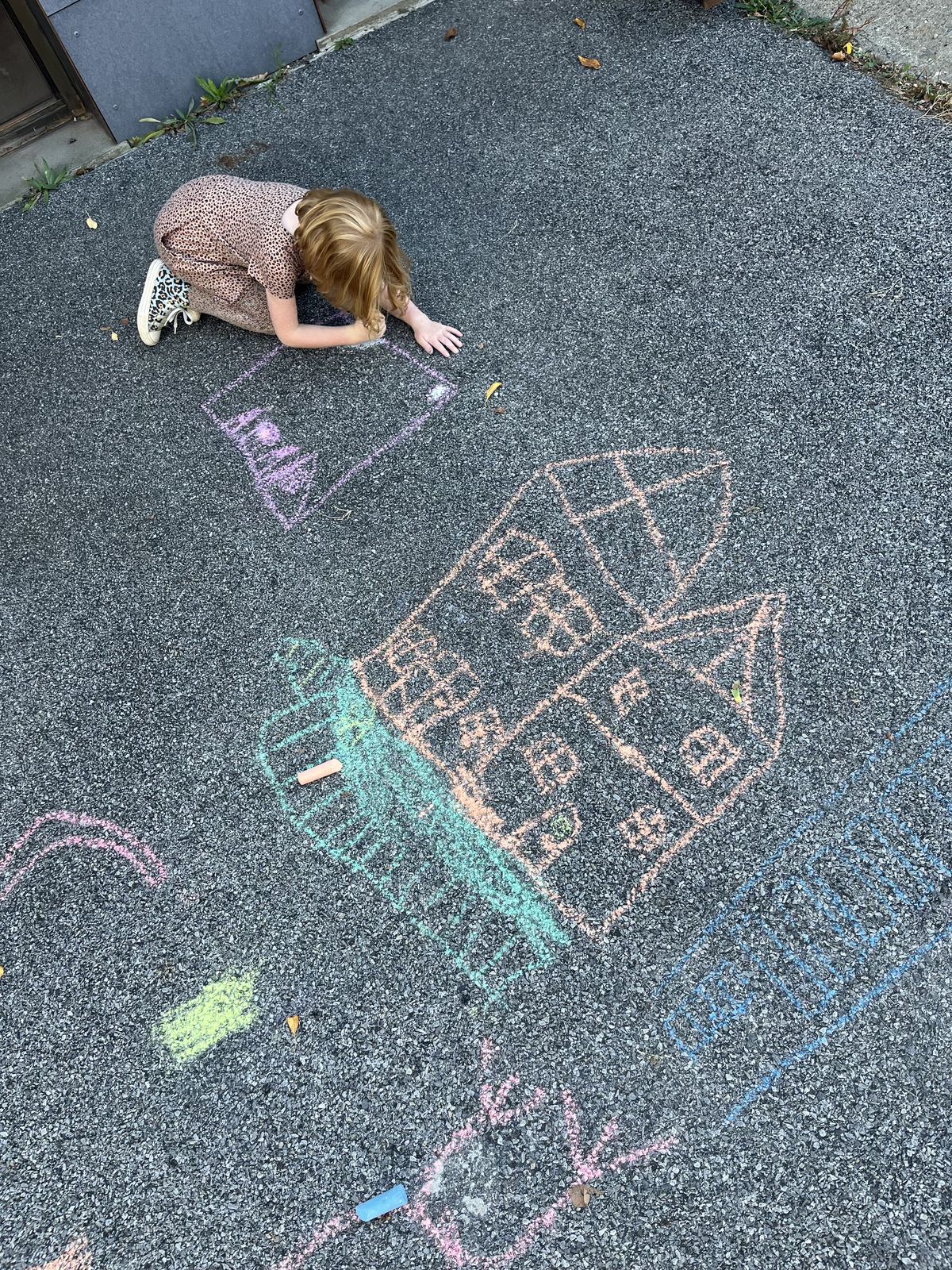 A young visitor chalks houses on the pavement